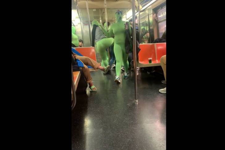 Women in green-colored jumpsuits shown on video attacking two people on board a subway.